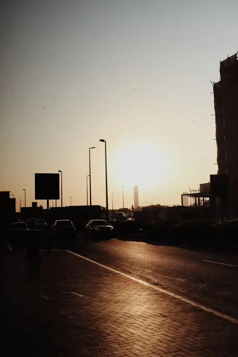 Hazy city street with the sun low over the road. Photo by Kiran Johns