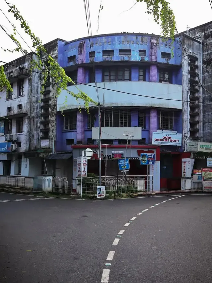 Curved blue and purple building of the Cochin Charitable Society on a street corner. Photo by Kiran Johns