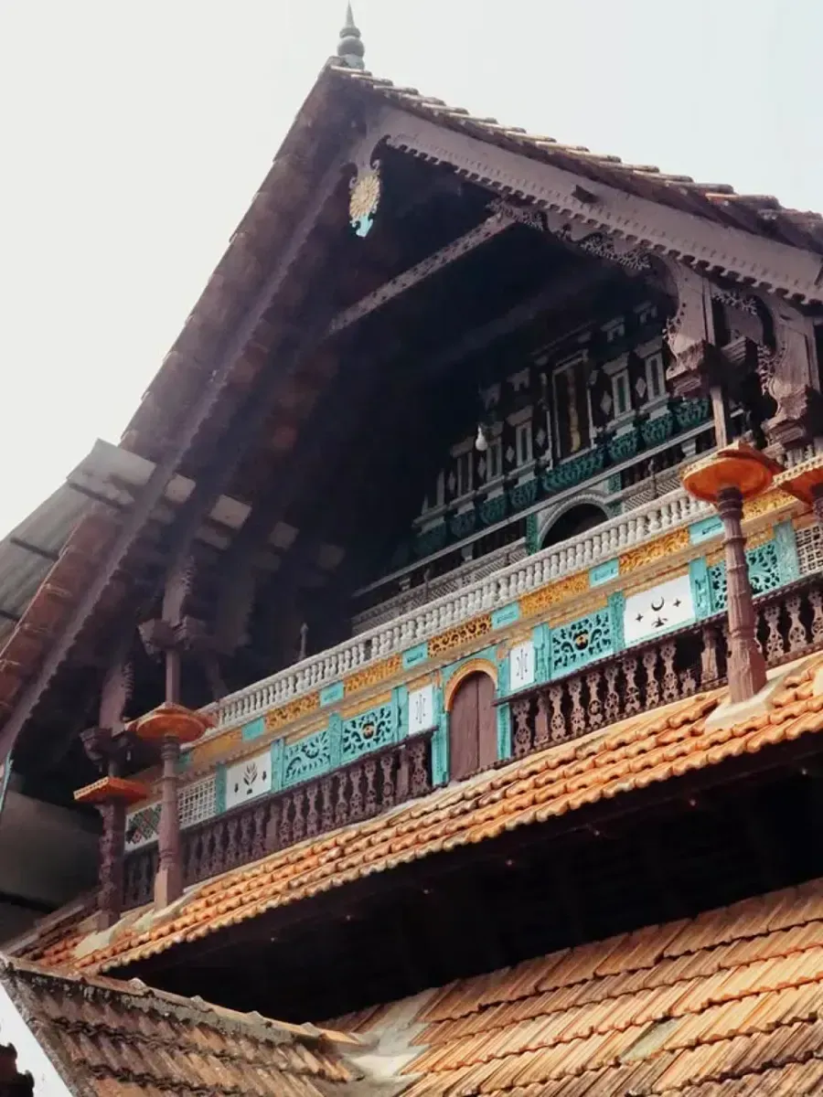 Looking up at a carved Kerala mosque roof with teal and terracotta details. Photo by Kiran Johns