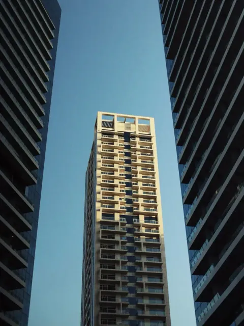 Looking up between towers at a sunlit high-rise. Photo by Kiran Johns